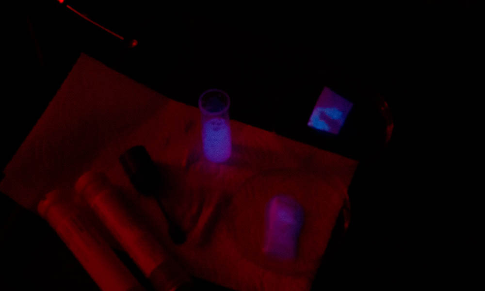 Fotografie des Experiments zum Nachweis von Blut. Die Blutprobe leuchtet schwach blau. Aus dem Experimentierkasten «Chemisches Leuchten» von Kosmos. 