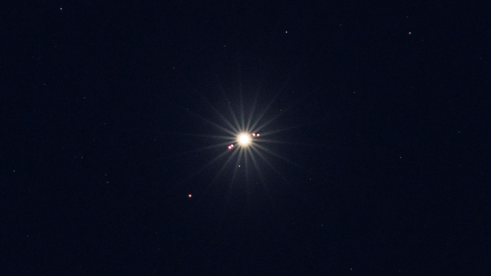 Fotografie (Ausschnitt) mit einer DSLR durch ein 300 mm Teleobjektiv. Ein Stativ ist ein Muss. Die vier Galileischen  Monde sind sehr gut zu sehen.